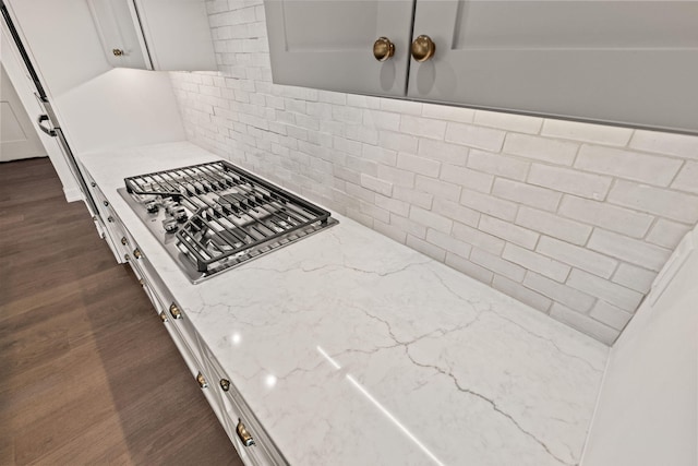 kitchen with white cabinetry, decorative backsplash, light stone countertops, and dark hardwood / wood-style floors