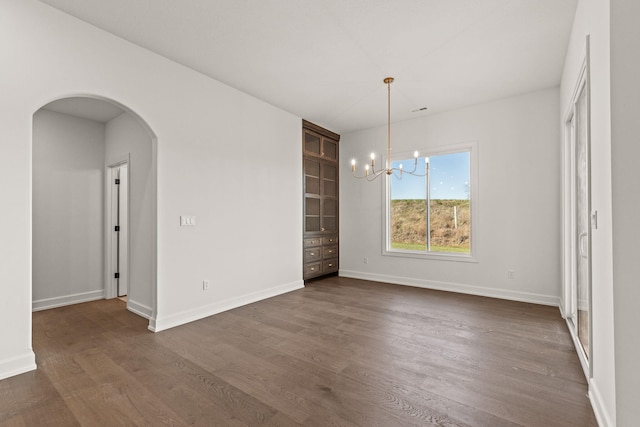 unfurnished dining area with dark hardwood / wood-style floors and an inviting chandelier