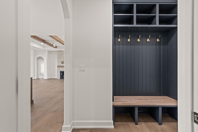 mudroom with beam ceiling, a large fireplace, and wood-type flooring