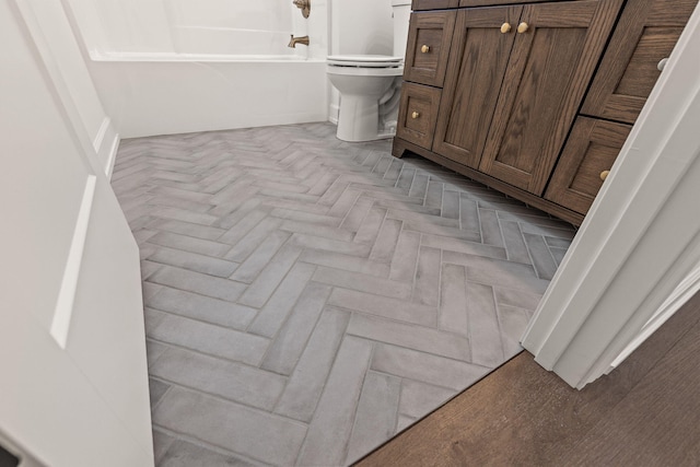 bathroom with shower / bathing tub combination, toilet, and parquet flooring