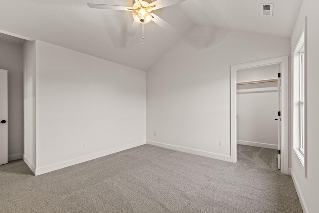 unfurnished bedroom featuring carpet, a walk in closet, vaulted ceiling, and ceiling fan