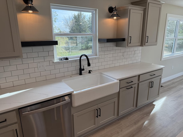 kitchen with a healthy amount of sunlight, sink, stainless steel dishwasher, and light hardwood / wood-style floors