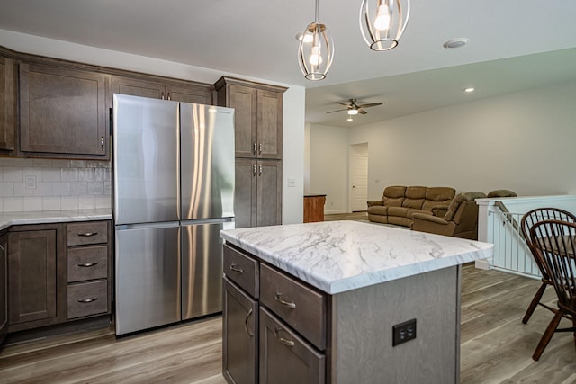 kitchen featuring stainless steel fridge, a center island, pendant lighting, and hardwood / wood-style flooring