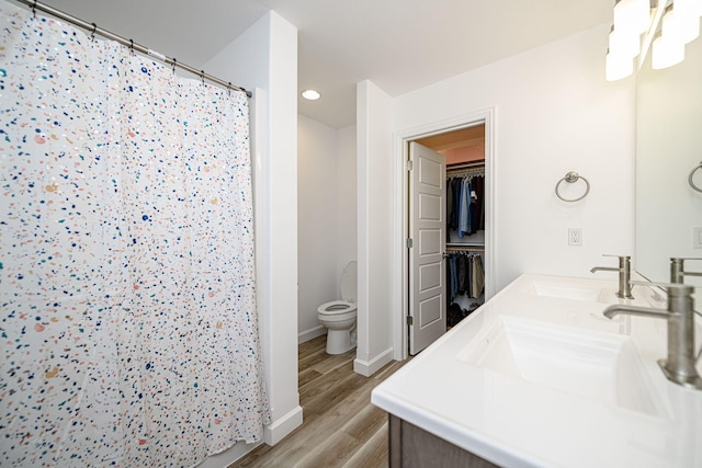 bathroom with hardwood / wood-style floors, vanity, toilet, and curtained shower