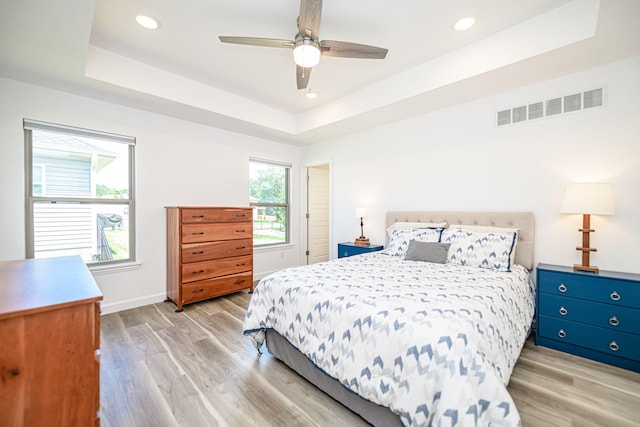 bedroom featuring a tray ceiling, ceiling fan, and light hardwood / wood-style floors