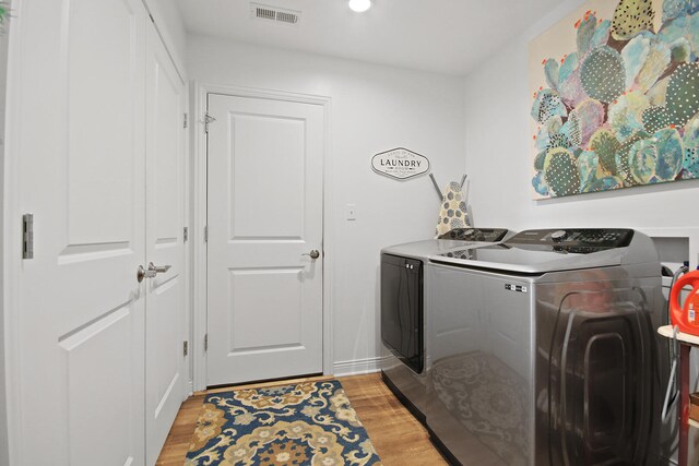 clothes washing area featuring washer and clothes dryer and light wood-type flooring