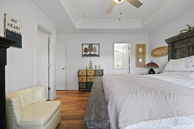 bedroom featuring dark hardwood / wood-style floors, ceiling fan, a raised ceiling, and connected bathroom