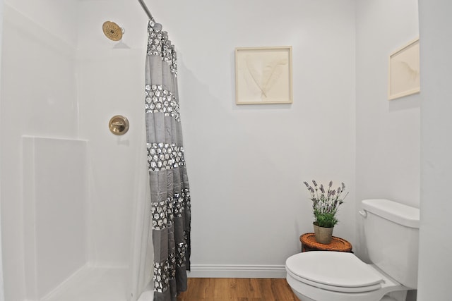 bathroom with hardwood / wood-style flooring, curtained shower, and toilet