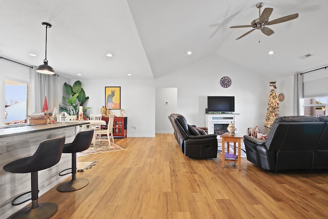 living room featuring vaulted ceiling, light hardwood / wood-style flooring, ceiling fan, and a healthy amount of sunlight