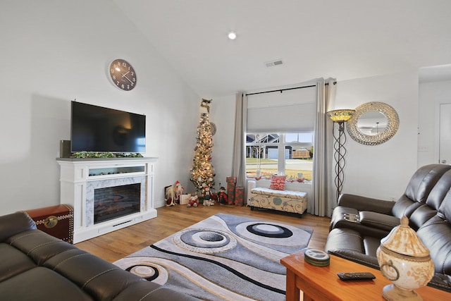 living room with a high end fireplace, lofted ceiling, and hardwood / wood-style flooring