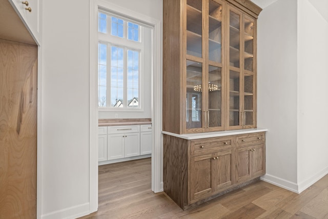 bar featuring white cabinets and light hardwood / wood-style flooring