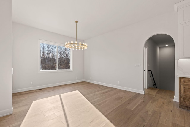 unfurnished room with light wood-type flooring and a chandelier