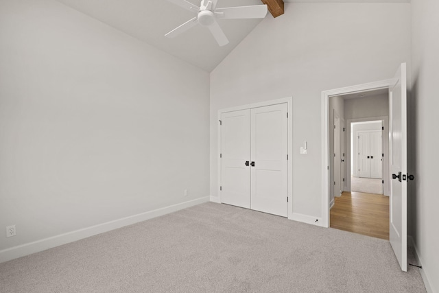 unfurnished bedroom featuring beam ceiling, ceiling fan, high vaulted ceiling, light carpet, and a closet