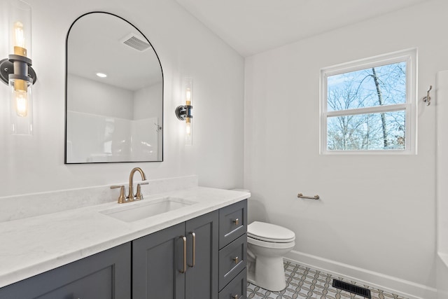 bathroom with toilet, vanity, and walk in shower