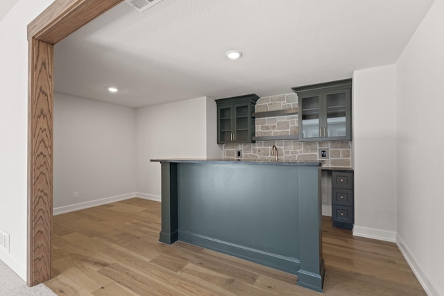 bar with tasteful backsplash, hardwood / wood-style floors, and sink