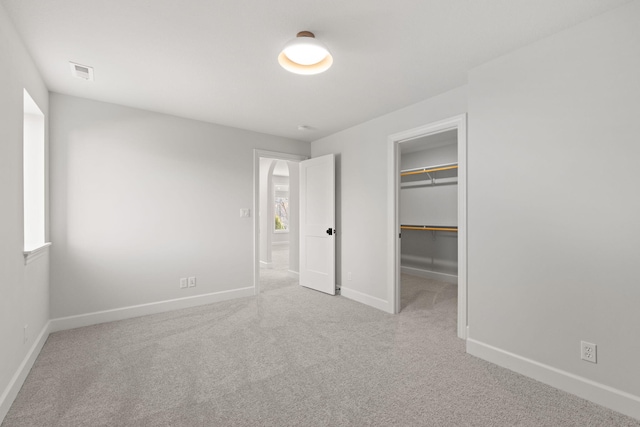 unfurnished bedroom featuring light carpet, a spacious closet, and a closet