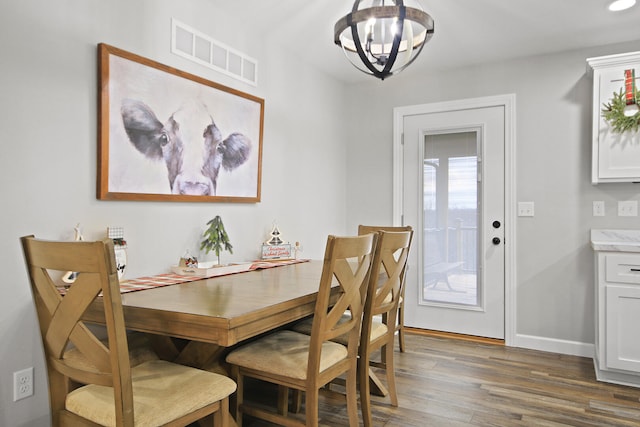 dining space with dark hardwood / wood-style flooring and a chandelier