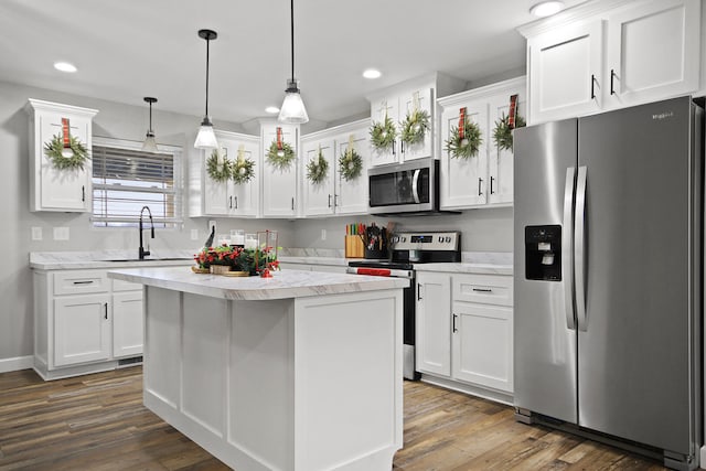 kitchen featuring stainless steel appliances, a kitchen island, white cabinetry, and pendant lighting