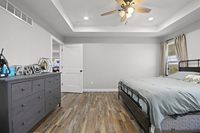 bedroom featuring ceiling fan, dark hardwood / wood-style flooring, and a raised ceiling