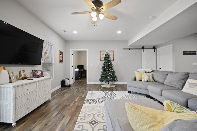 living room with ceiling fan, a barn door, and dark hardwood / wood-style flooring