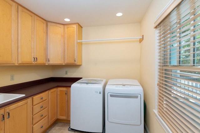 laundry area with cabinets, washing machine and dryer, and sink