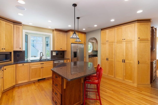 kitchen with a center island, hanging light fixtures, sink, decorative backsplash, and appliances with stainless steel finishes