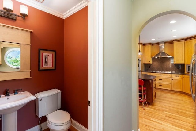 bathroom with sink, crown molding, hardwood / wood-style floors, toilet, and decorative backsplash