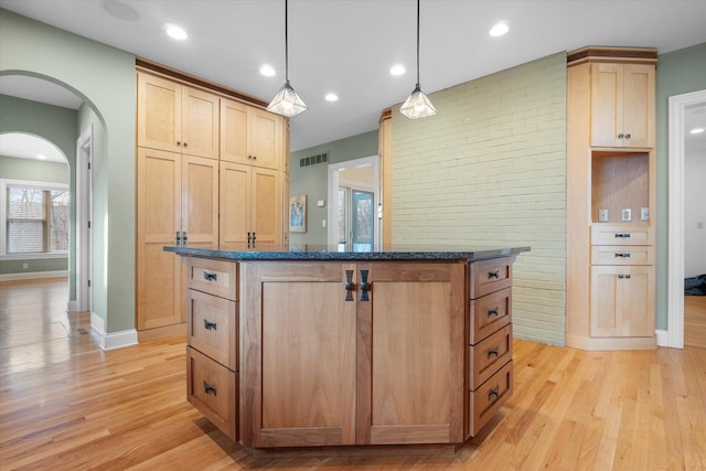 kitchen with light brown cabinetry, pendant lighting, a kitchen island, and light hardwood / wood-style floors