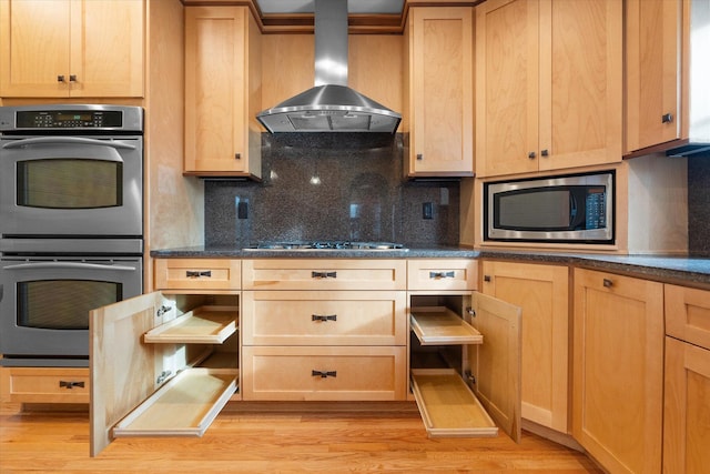 513 Rockhill Rd, Columbia, MO 65201 - kitchen featuring wall chimney exhaust hood, stainless steel appliances, light brown cabinetry, light wood finished floors, and tasteful backsplash
