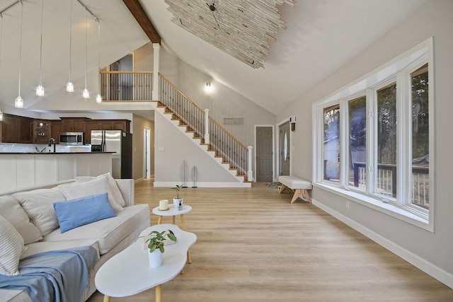 living room featuring sink, high vaulted ceiling, beamed ceiling, and light hardwood / wood-style flooring