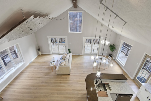 living room with a chandelier, a towering ceiling, and light hardwood / wood-style flooring