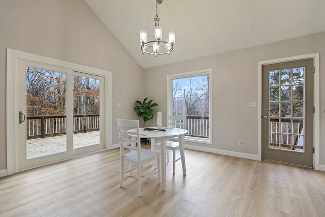 dining room with a chandelier, high vaulted ceiling, and light hardwood / wood-style flooring