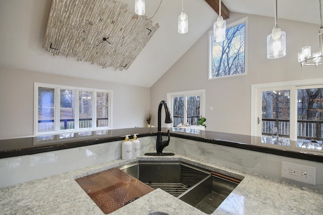 kitchen with beam ceiling, high vaulted ceiling, hanging light fixtures, and light stone counters