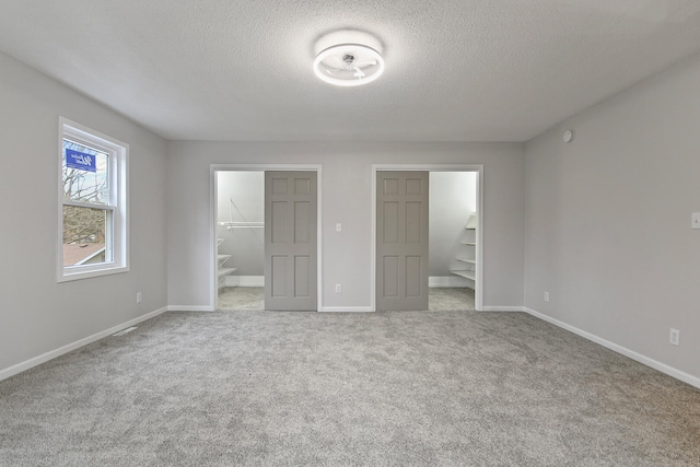 unfurnished bedroom with a textured ceiling, a walk in closet, and carpet floors