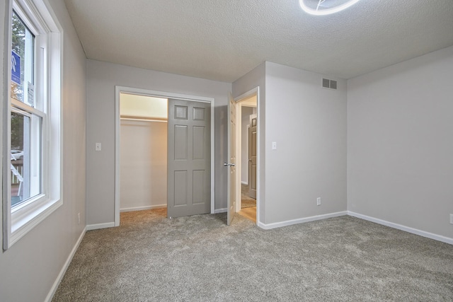 unfurnished bedroom featuring light colored carpet, a textured ceiling, and a closet