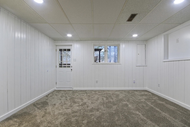 carpeted spare room with wooden walls