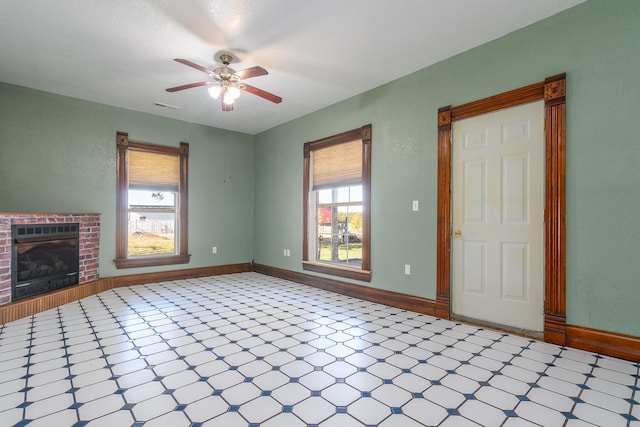 unfurnished living room with ceiling fan and a fireplace