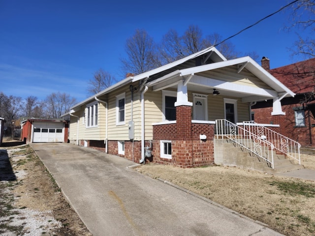 bungalow-style home with a ceiling fan, driveway, a porch, an outdoor structure, and a garage