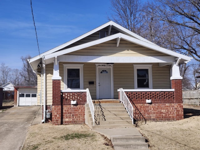 bungalow-style home featuring brick siding, covered porch, concrete driveway, and an outdoor structure