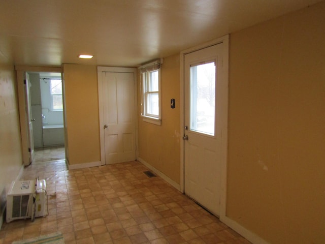 foyer featuring a wall mounted AC and a healthy amount of sunlight