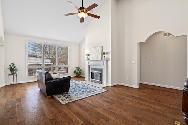 living area featuring visible vents, ceiling fan, wood finished floors, a tile fireplace, and baseboards