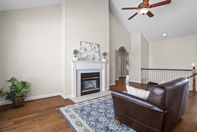 living area with baseboards, a fireplace, arched walkways, and wood finished floors