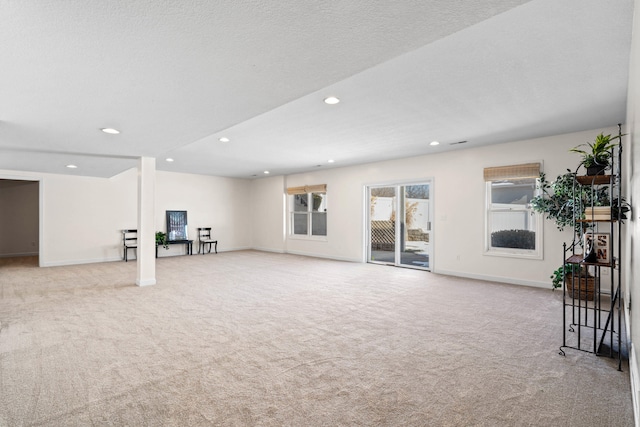 unfurnished living room featuring baseboards, carpet floors, a textured ceiling, and recessed lighting