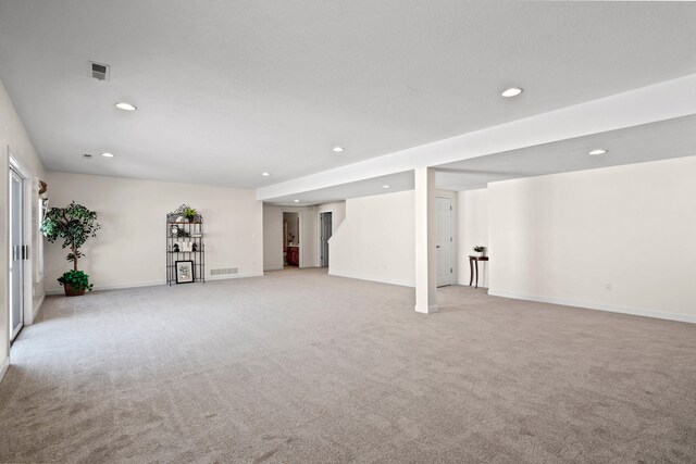 finished below grade area featuring light carpet, visible vents, and recessed lighting