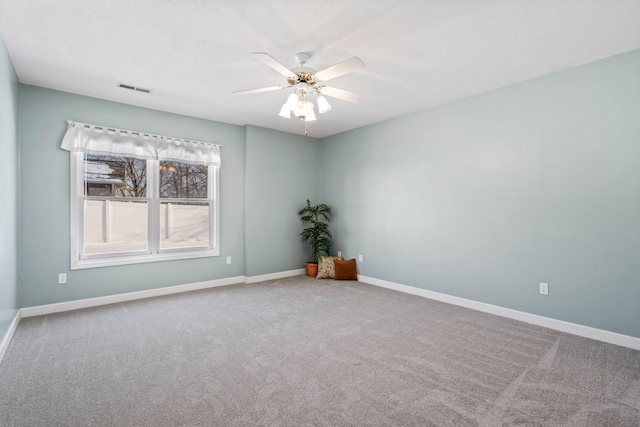 carpeted empty room featuring visible vents, ceiling fan, and baseboards