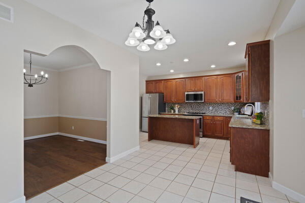 kitchen featuring a chandelier, visible vents, appliances with stainless steel finishes, decorative backsplash, and a center island