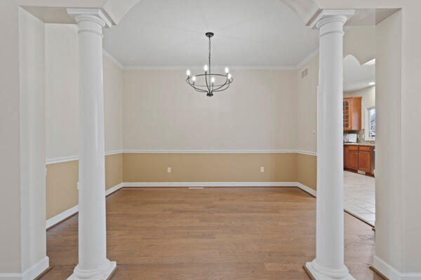 unfurnished dining area with decorative columns and light wood-style floors