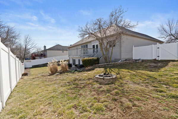 back of property with a gate, a fenced backyard, a yard, and a fire pit