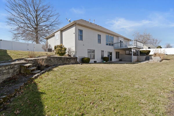 back of house featuring a fenced backyard, a deck, and a lawn