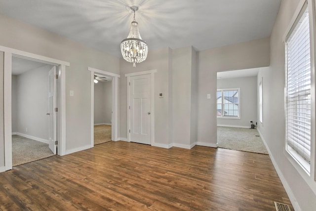 entryway with dark hardwood / wood-style floors and ceiling fan with notable chandelier